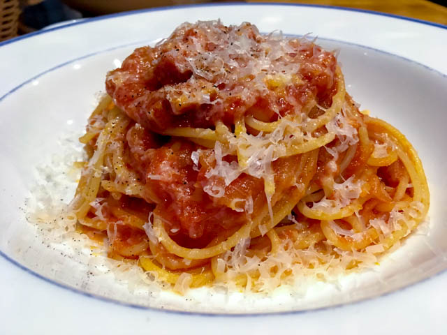 丸いお皿にうず高く盛られたトマトベースのスパゲティ